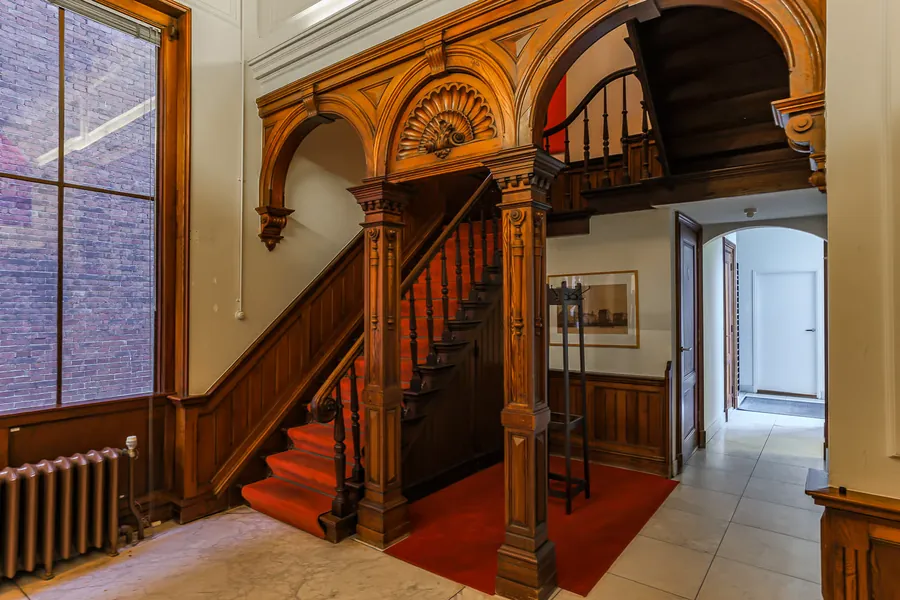 Het trappenhuis in het pand van Studio Progressus met houten gebogen pilaren en een rode loper